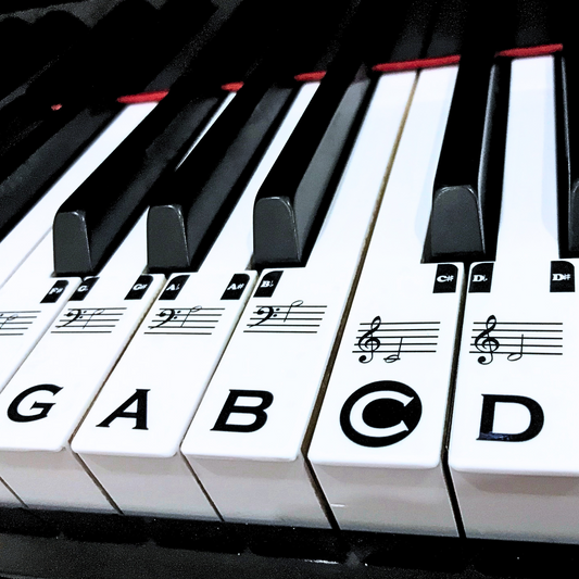 A close up of piano key stickers on a piano, that are there to help you learn how to read notes